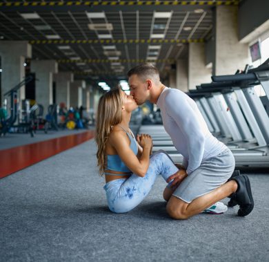 Love couple kissing, fitness training in gym. Athletic man and woman on workout in sport club, active healthy lifestyle, physical wellness